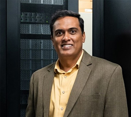 Giri Prakash in front of the Cumulus high performance computing cluster